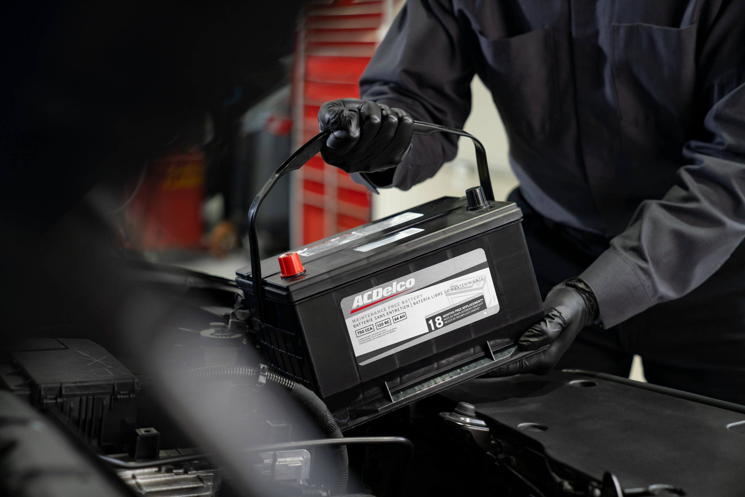 Arnie Bauer GMC service technician replacing a truck battery with a factory-specified ACDelco 12V battery.